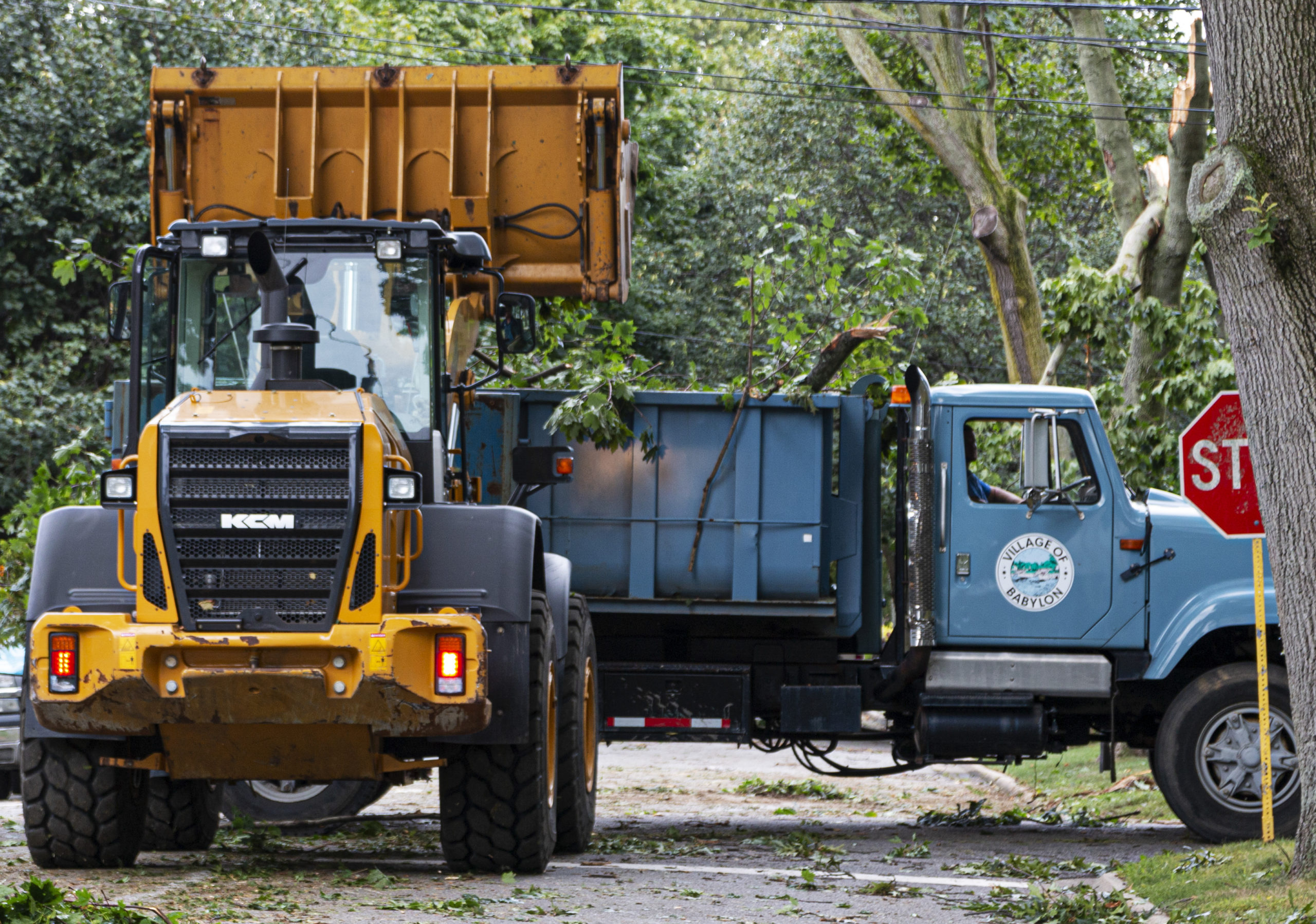 Workers in trucks removing storm damage from roads